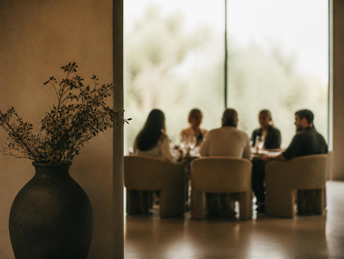 A small group seated in conversation around a table in soft daylight